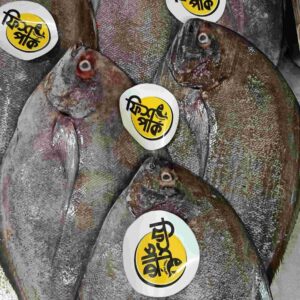 Fresh whole Black Pomfret fish with distinctive flat profiles and dark silver-grey scales, tagged with bright yellow Fish Park brand labels on a metal display counter.